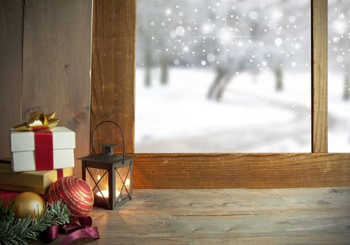 Christmas gifts and decorations next to a window with snow outdoors