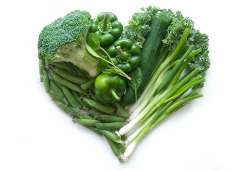 Selection of green vegetables and leaves including kale and broccoli in the shape of a heart over a whtie background