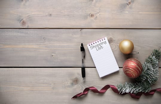 Notepad with Christmas shopping list over a wooden background