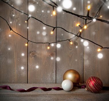 Christmas decorative lights with baubles on a wooden background with space