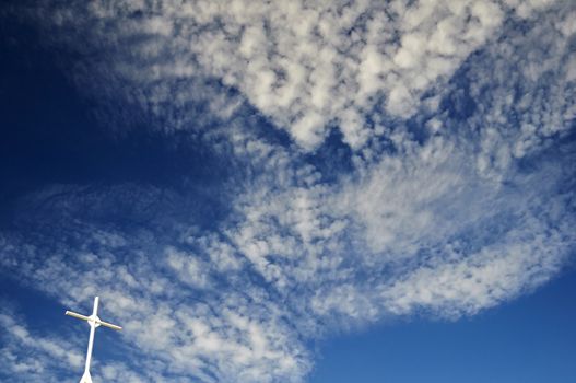 White cross in the blue cloudy sky