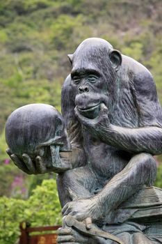 Hainan, China - 09 April, 2012  : Monkey Island Research Park - a Gorilla Statue,  by a large bronze-like statue of a monkey sitting on a pile of books with a skull in a pawon on Monkey Island 9 April 2012 , China