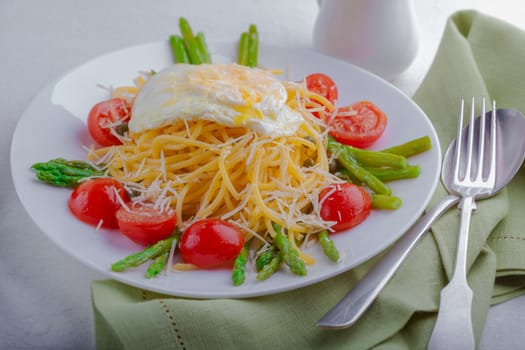 Spaghetti with egg and vegetables on a white plate