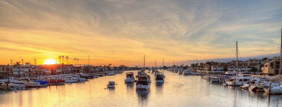 Balboa Island harbor at sunset with ships and sailboats visible from the bridge that leads into Balboa Island, Southern California, USA