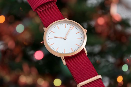Red nylon strap wrist watch in Christmas time in front of Christmas tree lights background