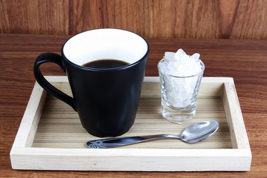 Black Coffee and rock sugar in wood tray on wood table