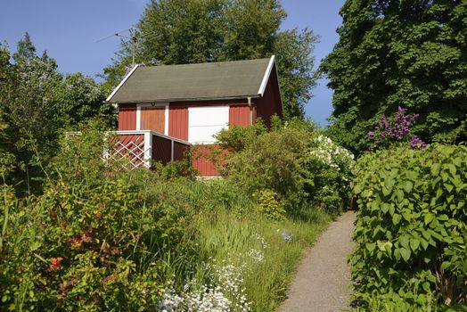 Idyllic red cottage in botanical garden.