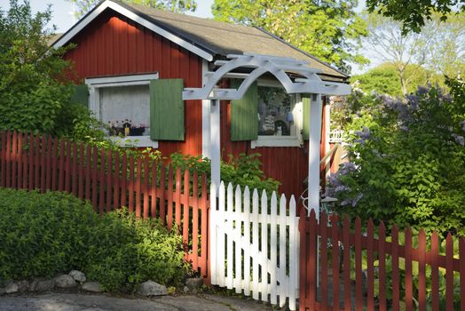 Idyllic red cottage in botanical garden.