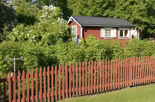 Idyllic red cottage in botanical garden.