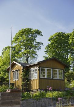 Idyllic yellow cottage in botanical garden.