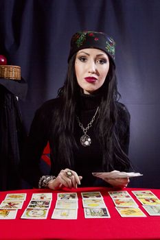 Sorceress wonders by Tarot cards on a black background