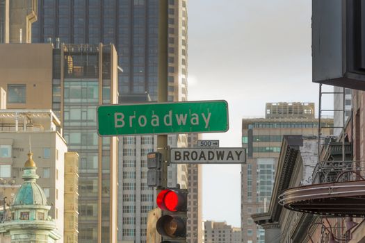 road sign of broadway in san francisco with a red light and buildings in the background