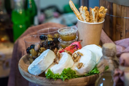 Camembert with nuts and olives on wooden board