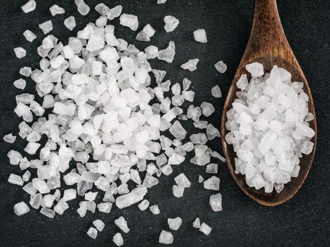 coarse sea salt in spoon on stone close up. Copy space. Flat lay or top view