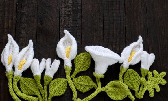 Amazing green background with handmade product, knitted flower as arum lily, tulip, morning glory flower knit from white yarn and green leaf make wonderful background for design