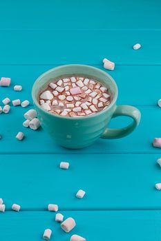 Blue cup of hot cocoa with marshmallows on blue wooden background
