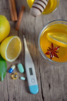 Hot lemon tea and pills on wooden table