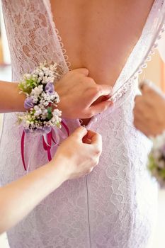 bridesmaids helps to dress for bride in wedding morning.