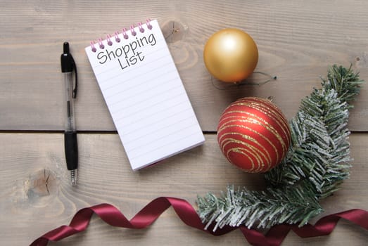 Notepad with Christmas shopping list over a wooden background