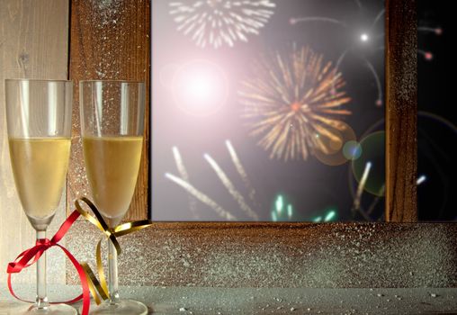 Firework display through a window with champagne glasses