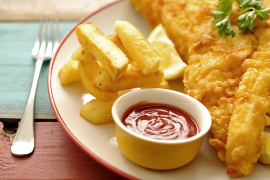 Deep fried battered fish on a plate with chips close up