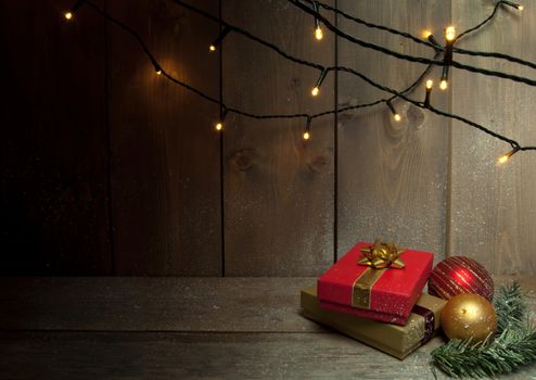 Christmas gifts and decorative lights on a wooden background with space