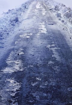 Snow covered winter road with shining streetlights in rural areas