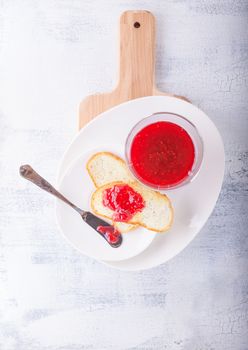 Raspberry jam in bowl with toast and knife