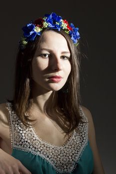 Portrait of a girl in a wreath of flowers on a dark background