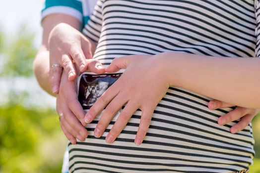 a woman and a man with the result of ultrasound, belly closeup