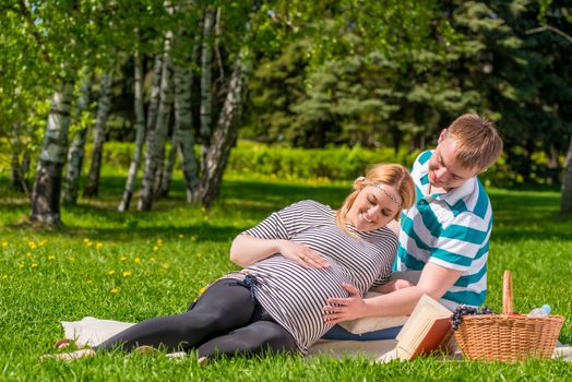 woman and a man spend their free time at the picnic, woman is pregnant