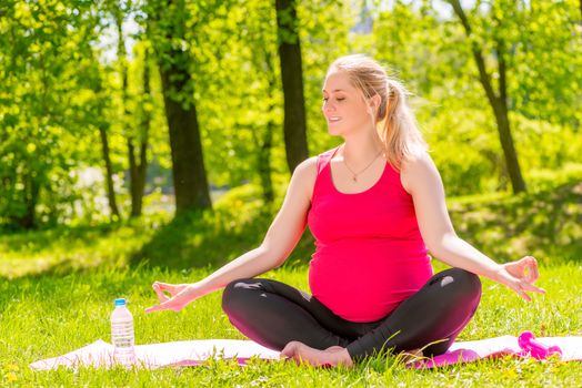 young pregnant woman in a lotus position doing yoga and relaxation