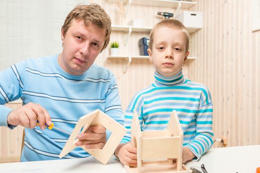 caring father teaches his son to build a bird feeder