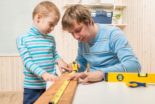 boy helps his father in the work of the carpenter