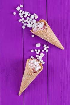 Marshmallows ice-cream and waffle cones on a purple background