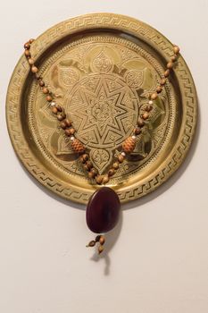 old metal plate on which carved antique ornament hanging on a white wall