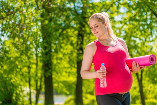 satisfied with the pregnant woman holding a yoga mat and water bottle