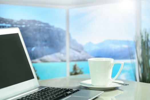 Cup of coffee next to a laptop on the background of the picturesque fjords
