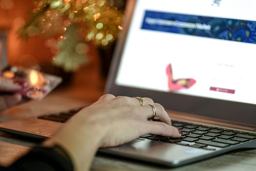 Woman doing Christmas e-shopping via laptop and credit card on the background of Christmas decorations