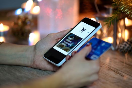 Woman makes Christmas shopping via smartphone and a credit card in the online store