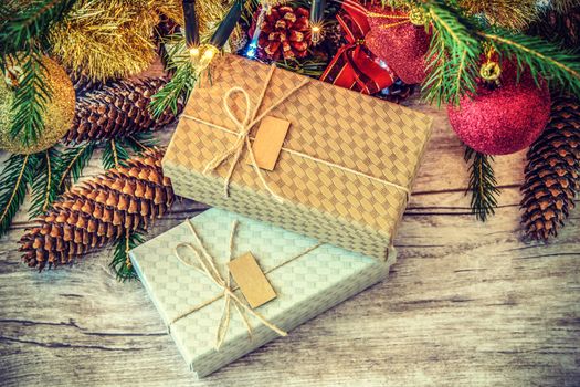 Overhead retro shot on cartons decorated with string and label on a wooden table under Christmas tree with cones