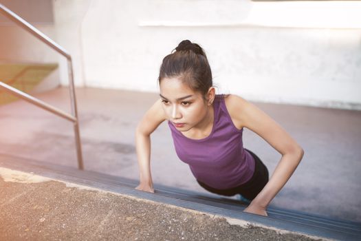 Sport urban Young athletic woman doing push-ups. Muscular and strong exercising.