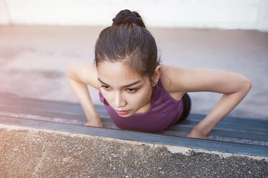 Sport urban Young athletic woman doing push-ups. Muscular and strong exercising.