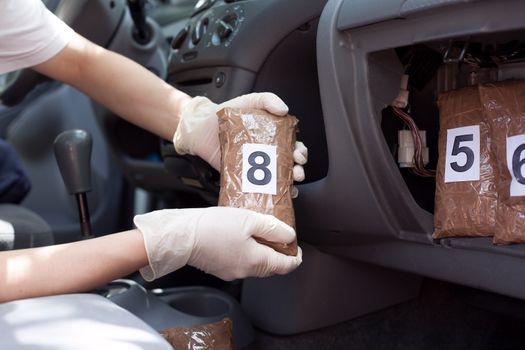 Policeman holding drug package found in secret compartment in a car