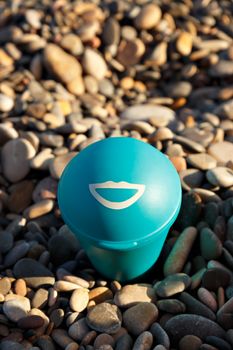 Blue beach ashtray with a drawn smile. Vertical image.