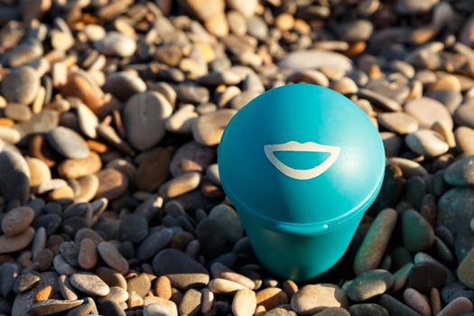 Blue beach ashtray with a drawn smile. Horizontal image.