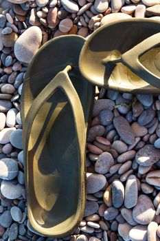 Green Flip Flops on a stones beach. Vertical image.