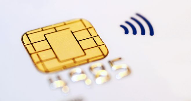 White credit card with closeup of a chip and contactless symbol. Macro shot.