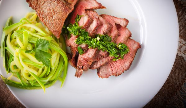 Zucchini pasta and meat on a white plate