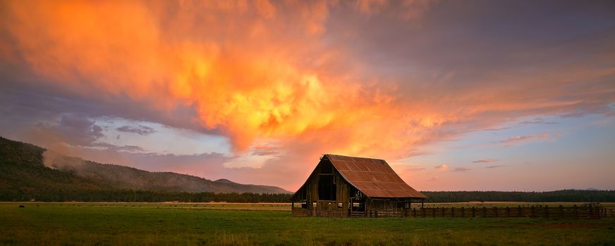 A barn with a vivid sunset clouds hovering above in Northern California.